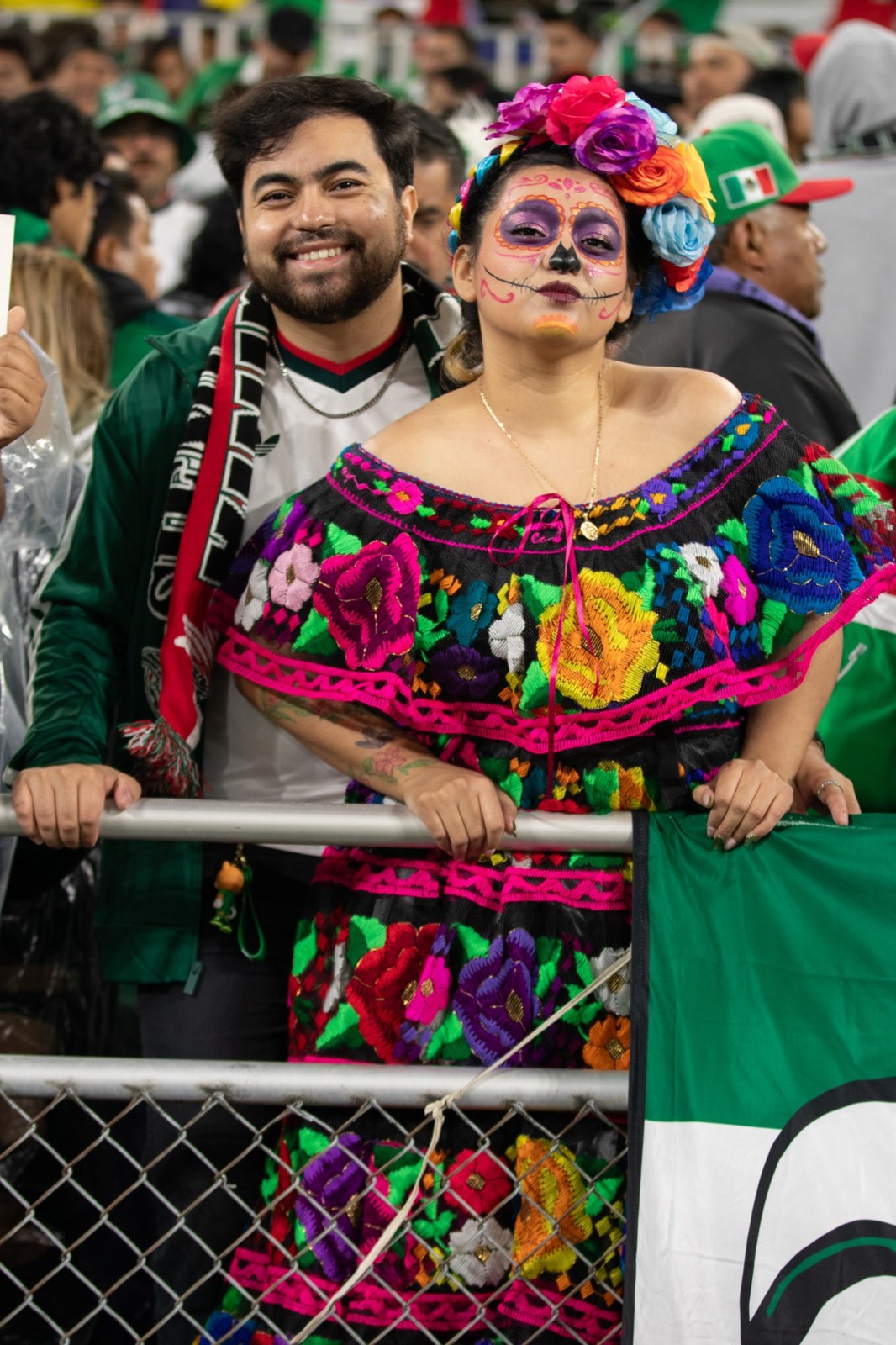 Colorful clothing and face paint celebrate Mexico in the crowd.