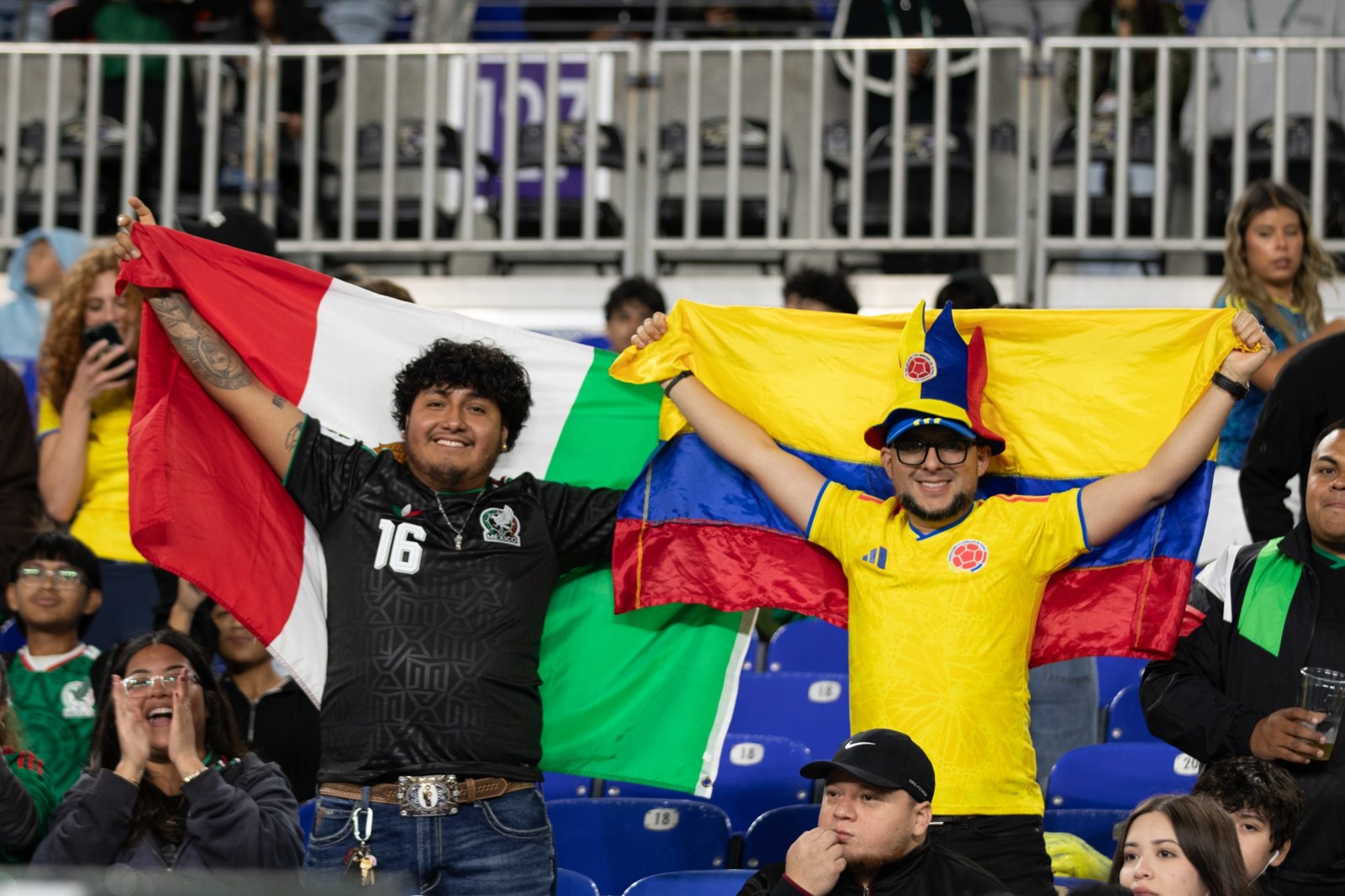 Supporters share a smile beneath Colombia and Mexico flags.