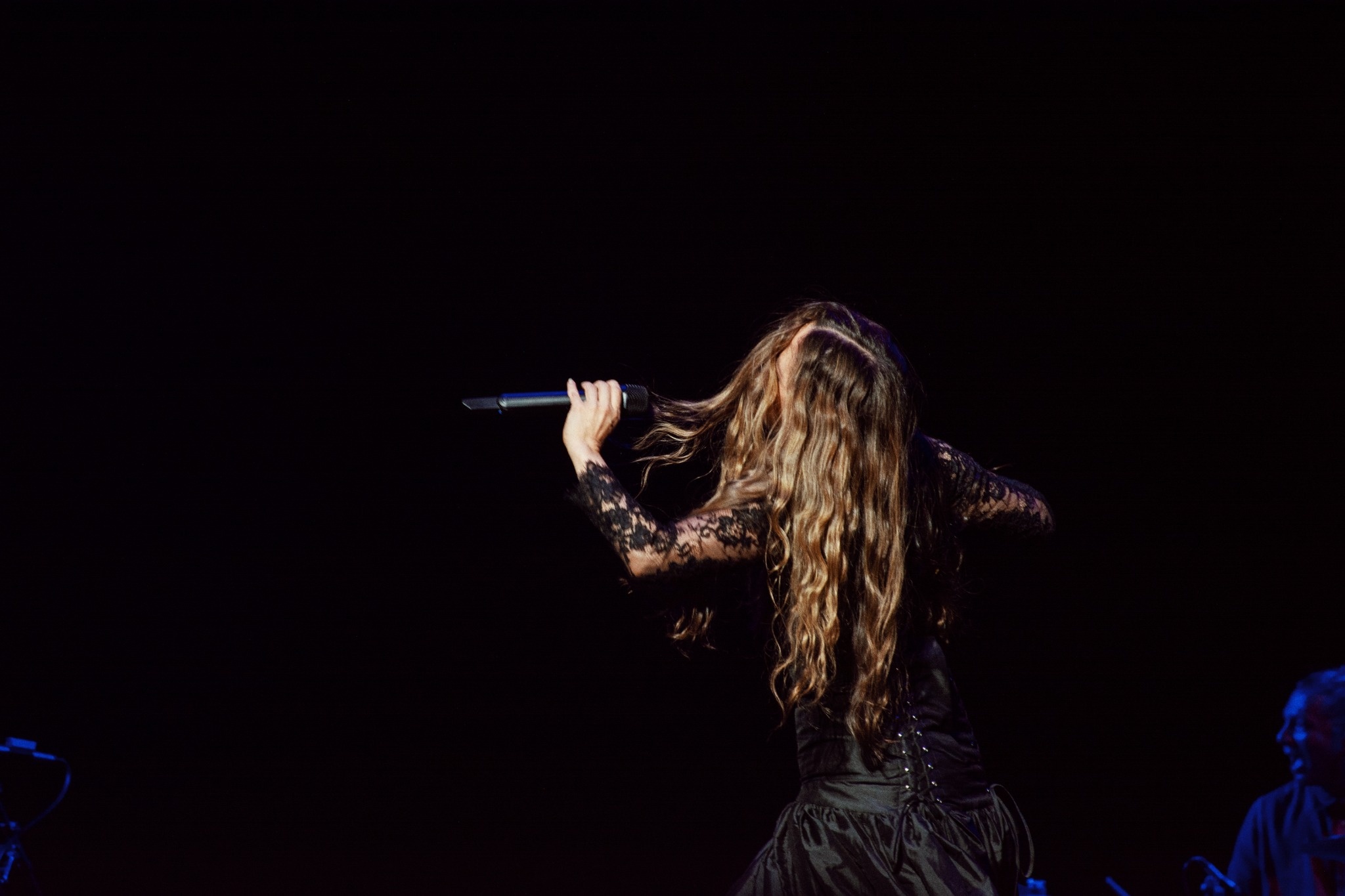 Rear view of Natalia Lafourcade singing onstage in a black dress.