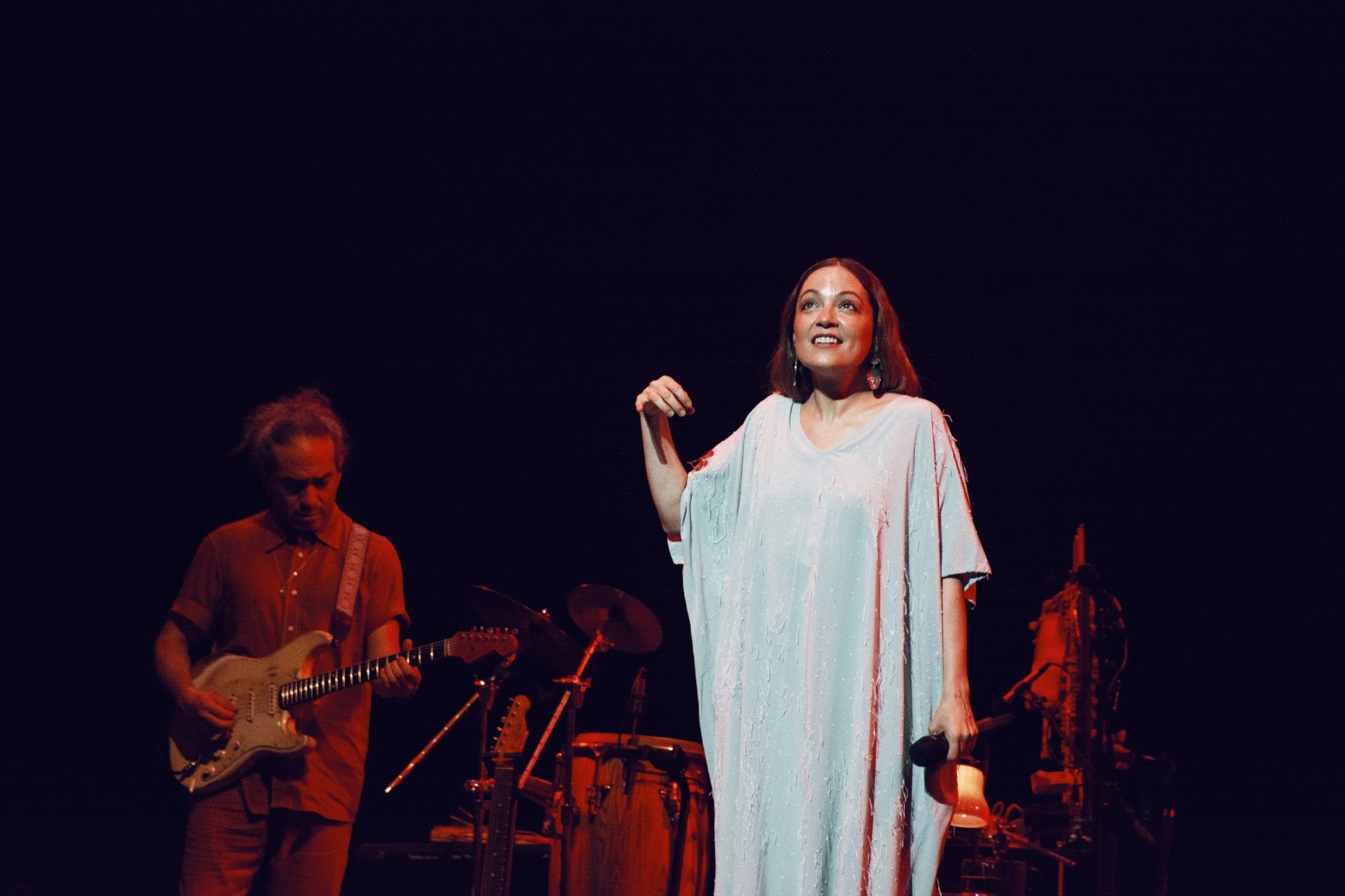 Natalia Lafourcade in a pale dress with musicians onstage.