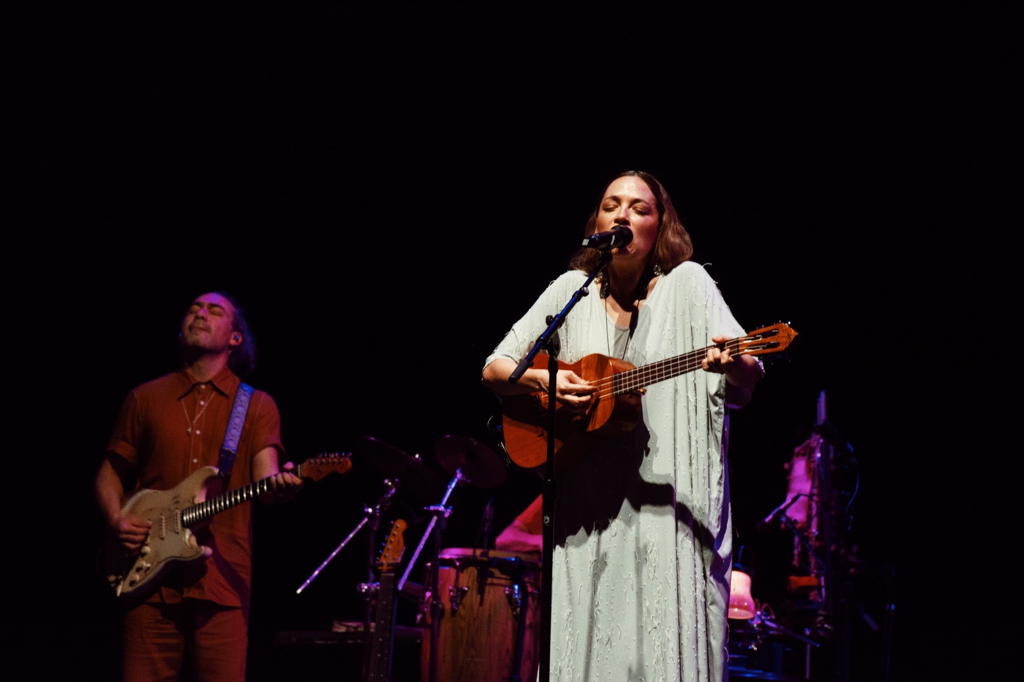 Natalia Lafourcade playing a small stringed instrument in a pale dress.
