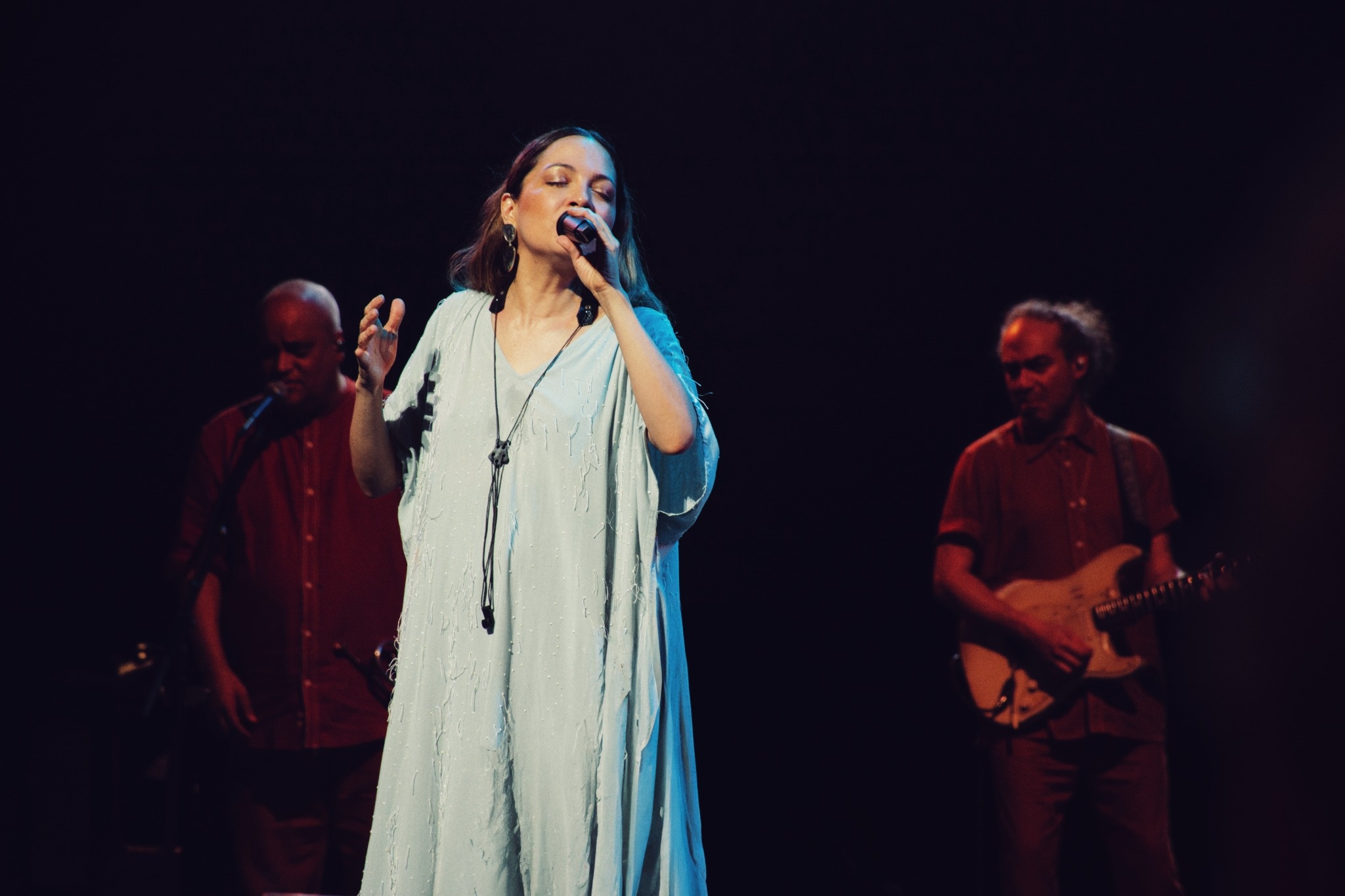 Natalia Lafourcade singing into a microphone in a pale dress.