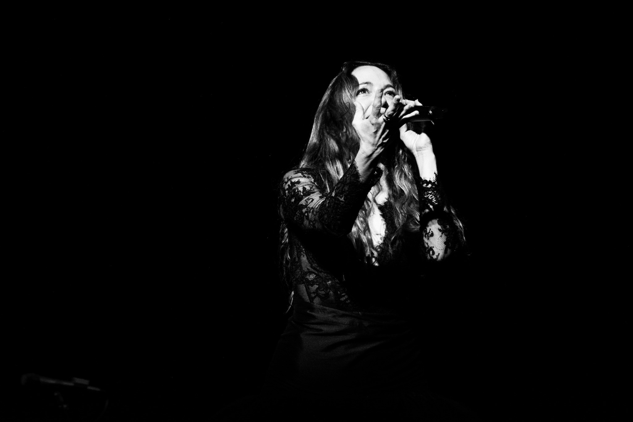 Black-and-white concert portrait of Natalia Lafourcade singing.